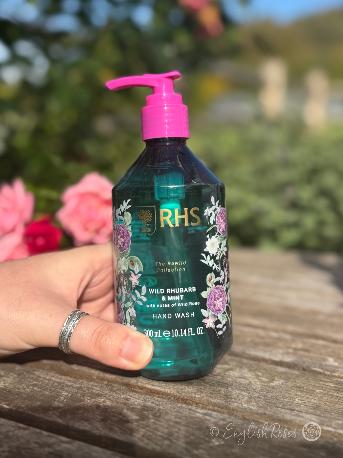 Hand Wash - Wild Rhubarb and Mint RHS The Rewild Collection 2 - A hand holding the bottle in a sunny garden